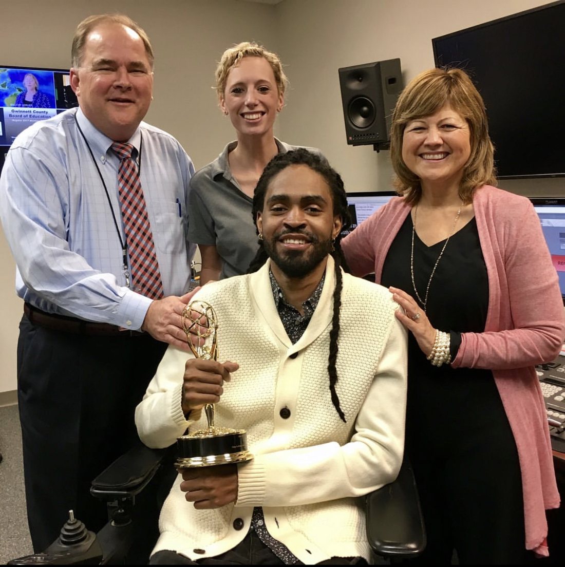 Que Crane holding an Emmy with colleagues